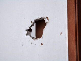 Cracked plaster wall with large irregular hole exposing interior space