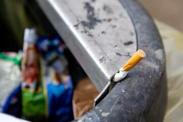 Cigarette stubbed on edge of public trash bin
