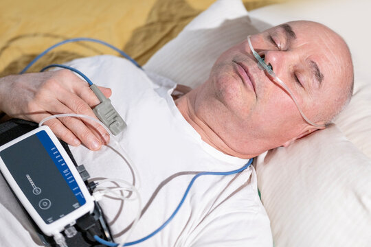 man wearing portable sleep tracker on abdomen, male patient with sleep and health monitoring device on abdomen and fingertip pulse oximeter