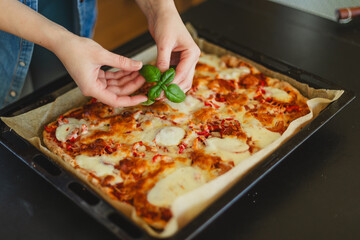 Cooking homemade pizza. Female hands making dough, adding sauce and ingredients.