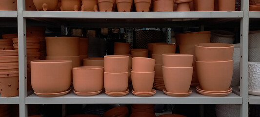 Terracotta flower pots neatly arranged on a store shelf. A warm-toned image showcasing gardening supplies and rustic pottery in a retail environment.