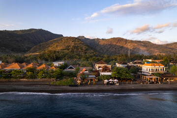 Breathtaking sunrise illuminating houses on black sand beach in amed, bali © Néstor
