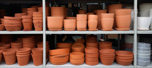 Terracotta flower pots neatly arranged on a store shelf. A warm-toned image showcasing gardening...