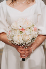Portrait of a bride with a bouquet in her hands. The composition focuses on the flowers and the...