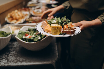 A hand reaches out for an appetizer placed among other treats on the festive table. The moment of real action, the atmosphere of a live celebration.