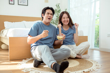 Couple Enjoying Popcorn Together While Sitting on the Floor in a Cozy Bedroom During the Afternoon