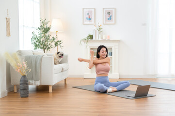 Woman Practicing Yoga at Home in a Serene Living Room With a Laptop and a Dog Nearby