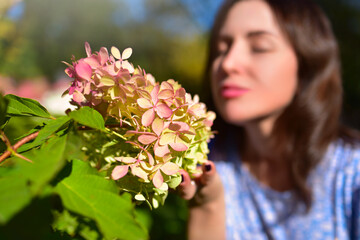 Close-up Focus on Pink Flowers with Woman Smelling in Background