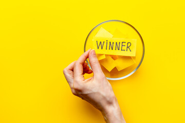Hand is holding raffle ticket winner near glass jar, top view. Luck and lottery concept