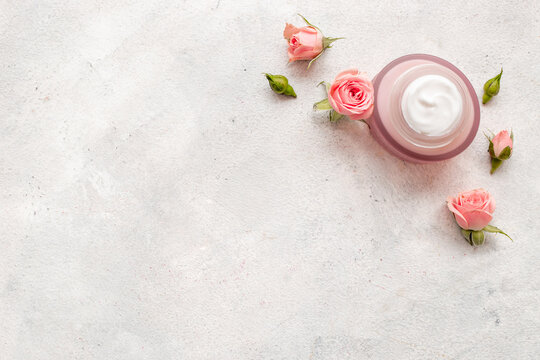 Skin care cosmetic crem with pink roses flowers, top view. Beauty routine concept