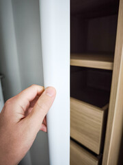 Modern bedroom wardrobe with sleek design showcasing open shelves and drawers, hand reaching for...