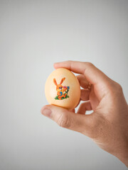 Colorful decorated egg held in hand showcasing a cheerful bunny design perfect for Easter...