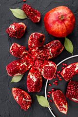 Top view of fresh ripe pomegranate and pieces on plate for eating, top view.