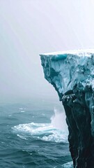 Dramatic iceberg cliff face meeting the turbulent ocean waters on a overcast day for a powerful seascape