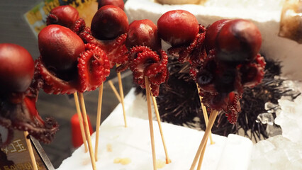 A skewered baby octopuses on wooden sticks .