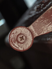 Close-up of a screw head and a part of a metal handle, against a dark background