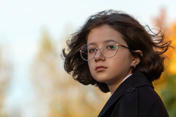 young girl with short brown hair and round glasses looks calmly into the distance