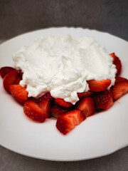 Fresh strawberries topped with whipped cream dessert on a white plate delicious treat concept. copy space