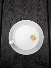 Creamy coffee cup Cappuccino with frothy milk on dark wooden table perfect for coffee lovers concept. copy space