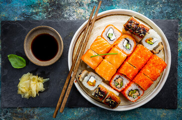Set of sushi and maki with soy sauce over blue stone background. Top view with copy space