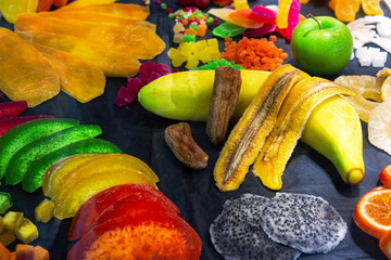 Various fruits (kiwi, mango, pineapple, papaya, banana, orange, lemon, apple, melon, dragon fruit) in display case of candy store. Dry fruits background.