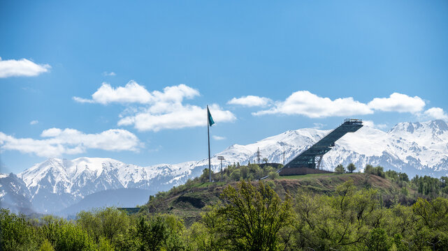 Ski jump and flag in Almaty with mountains in background