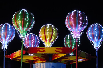 Line light art with balloon shaped objects in the circus with colorful lights in the background dark