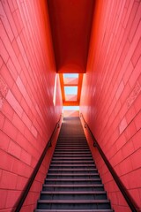 Obraz premium Perspective view of stairs ascending through a red brick structure towards a skylight.