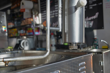 close-up view of a professional dough extruder dispensing churro batter over an industrial fryer in...