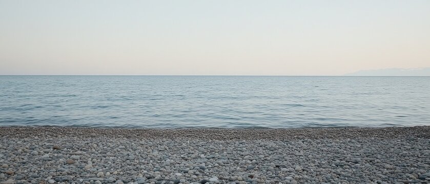 Calm sea meeting pebble beach at sunset, peaceful background for travel or relaxation