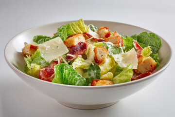 A fresh Caesar salad is presented in a clean white bowl against a white background