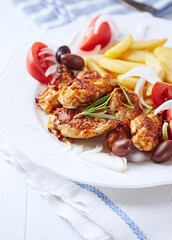 Spicy chicken wings with french fries and tomatoes. Close up.