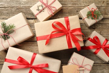 Gifts wrapped in kraft paper with fir tree branches on wooden background, flat lay