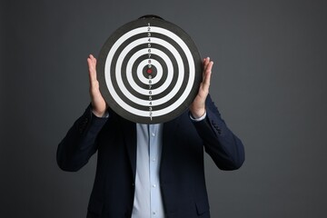 Targeting. Man with dart board on grey background