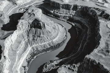 A stunning black and white aerial view of a river winding through a canyon, showcasing the rugged beauty of nature.