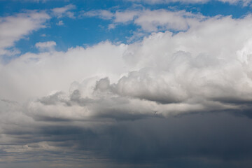 Thick storm clouds stretch across the sky with a visible curtain of rain falling below, creating a dramatic and moody atmosphere ample copy space.