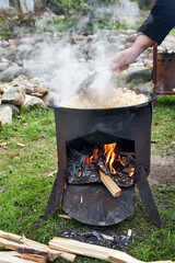 Top view of the cooking process of pilaf over an open fire in a cauldron on a grill, with boiling...