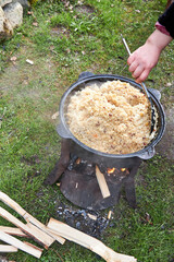 Top view of the cooking process of pilaf over an open fire in a cauldron on a grill, with boiling...