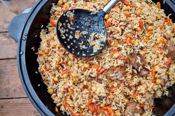 Top view of ready-made oriental pilaf in a black cauldron placed on an outdoor table