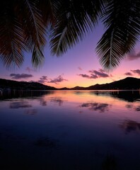 Obraz premium Beautiful sunset over calm waters surrounded by mountains and palm trees