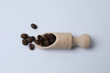 Hot coffee in a white coffee cup and many coffee beans scattered around 