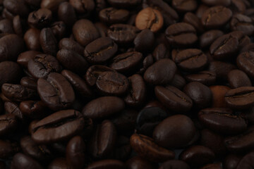 Hot coffee in a white coffee cup and many coffee beans scattered around 