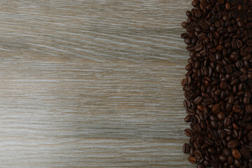 Hot coffee in a white coffee cup and many coffee beans scattered around 