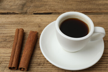 Hot coffee in a white coffee cup and many coffee beans scattered around 
