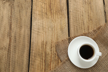 Hot coffee in a white coffee cup and many coffee beans scattered around 
