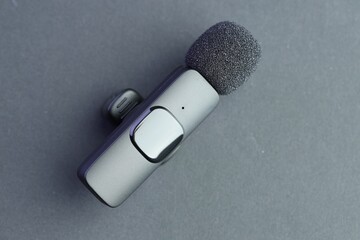 Lavalier microphone on grey background, top view