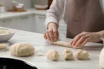 Making pretzels. Woman shaping dough at table in kitchen, closeup