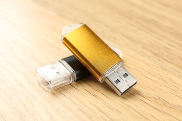 Two flash drives on wooden background, closeup