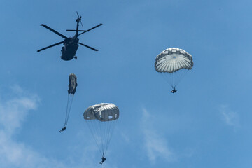 Army Paratroopers leap from a helicopter during a military training exercise, showcasing airborne deployment skills