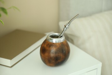 Traditional yerba mate tea and book on bedside table indoors